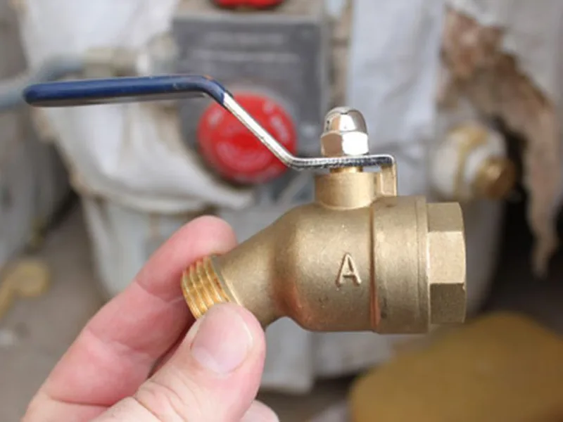 Plumber installing a brass drain valve on a south Phoenix AZ water heater